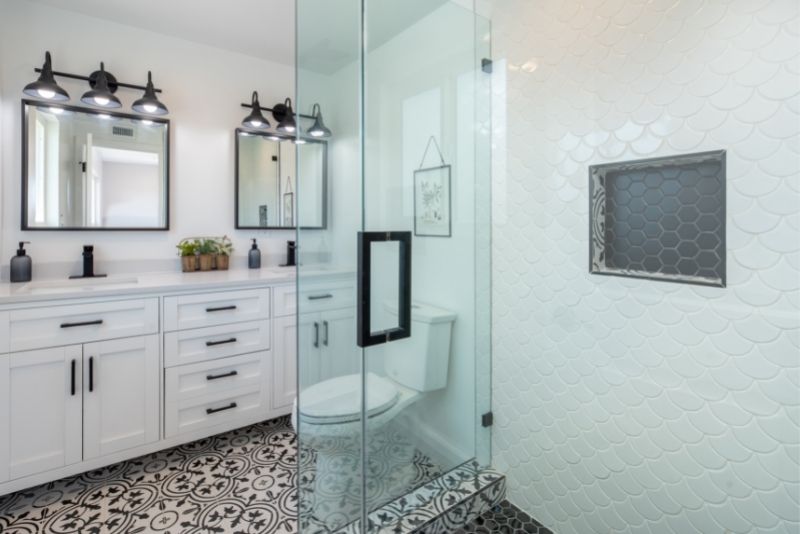A bathroom design with cabinets and glass door