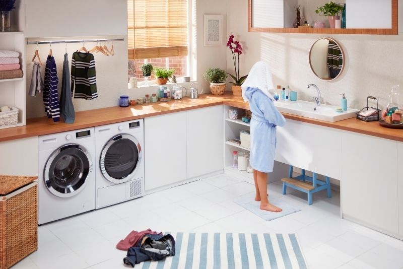 A laundry room with appliances and white cabinets